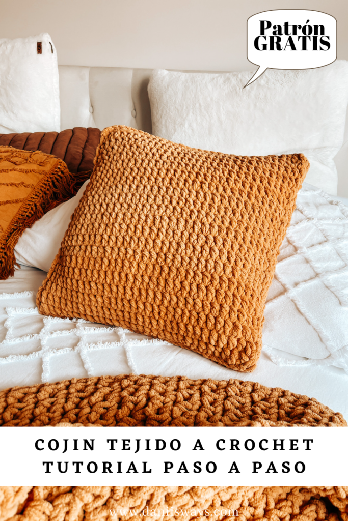 Una imagen de Pinterest con un cojín tejido a crochet de color amarillo sobre una cama blanca y en el texto se lee "cojín tejido a crochet, tutorial paso a paso"