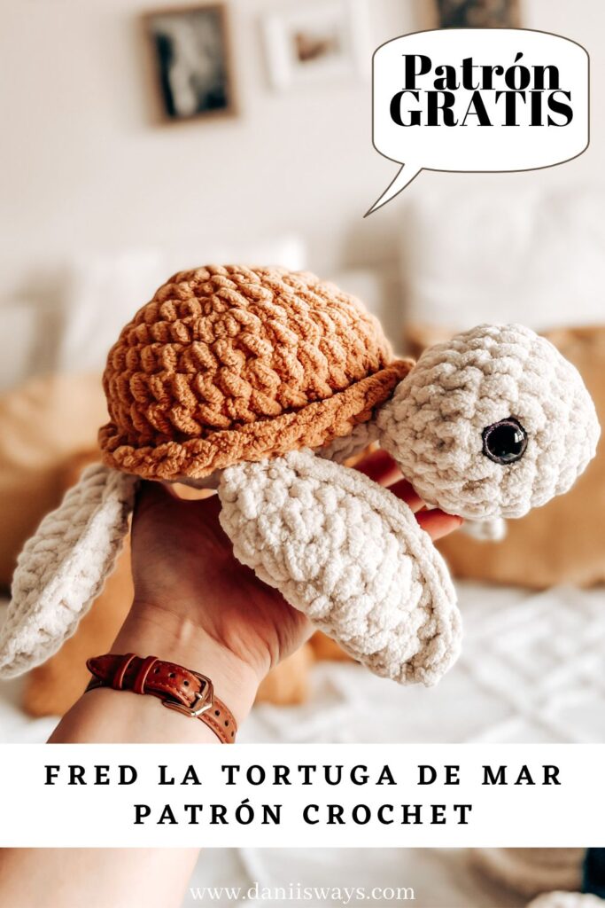 Una imagen de una tortuga tejida a crochet de color mostaza sobre una mano. La imagen lee "Patrón gratis a crochet"
